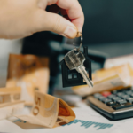 Mão segurando chave de casa com dinheiro e calculadora, custo da espera judicial