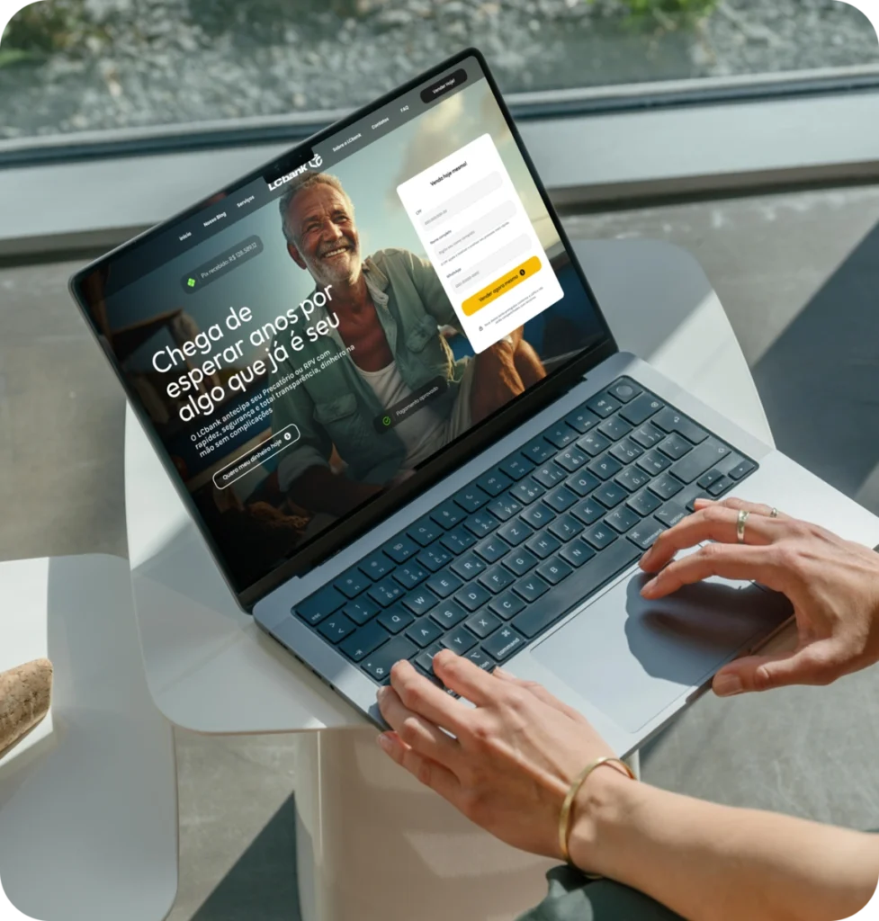 Laptop aberto no site do LCbank, com homem sorrindo e texto "Chega de esperar por algo que já é seu
