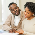 Par de africanos americanos analisando documentos e laptop, discutindo precatório federal